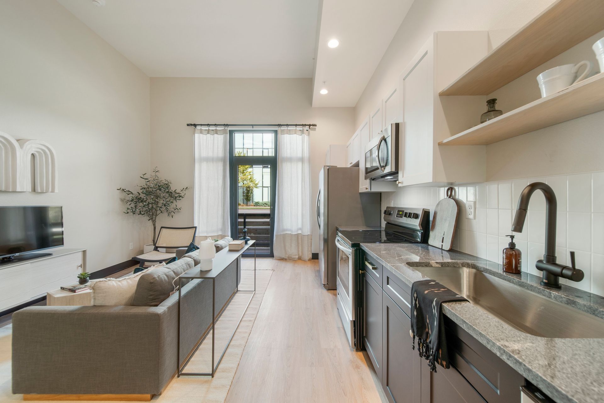 Modern apartment interior with kitchen, living area, and balcony access.