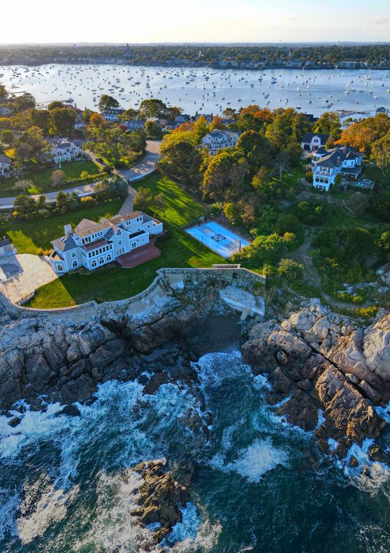 An aerial view of a house on a rocky cliff overlooking the ocean.