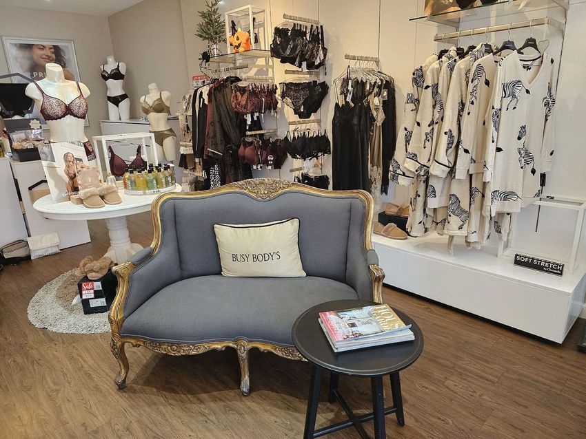 There is a couch in the middle of a lingerie store.