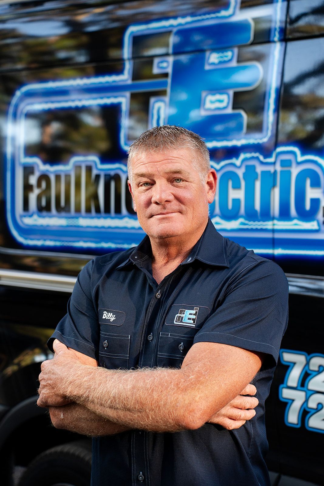 A man in a blue shirt is standing in front of a van.