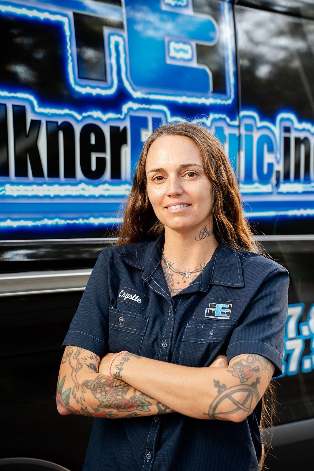 A woman in a blue shirt is standing in front of a truck.