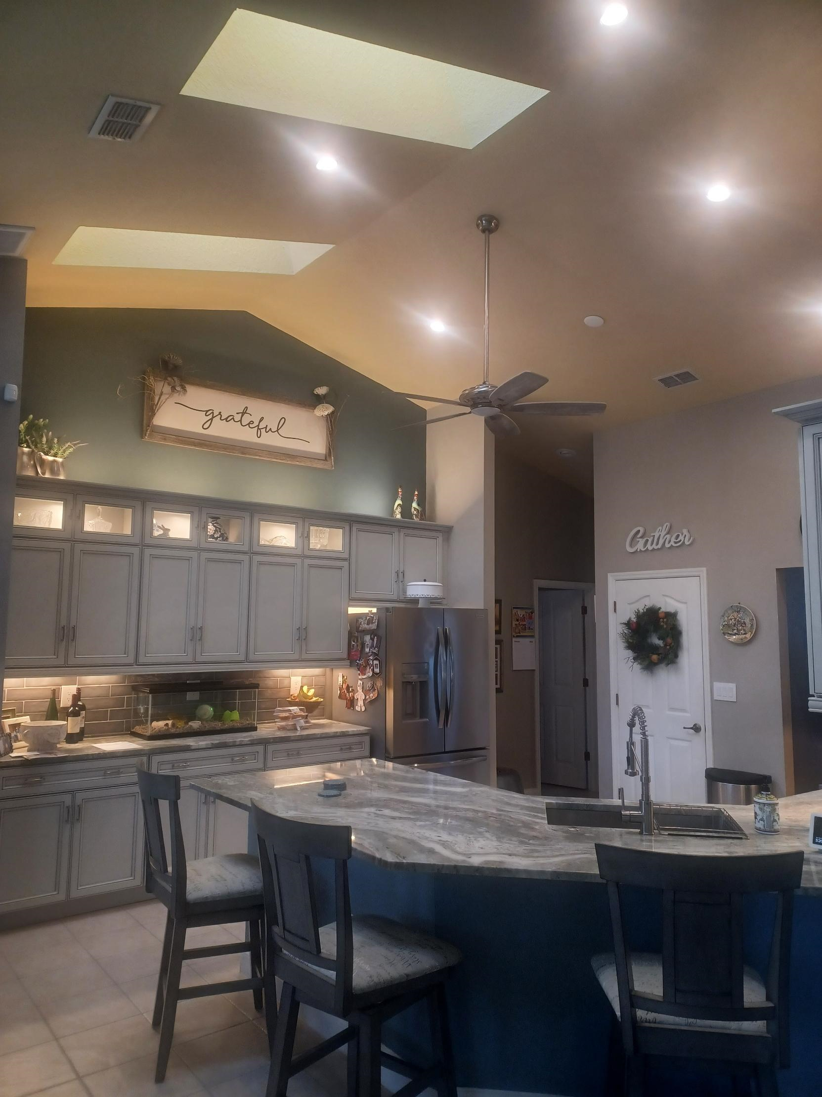 A kitchen with a large island and a ceiling fan.
