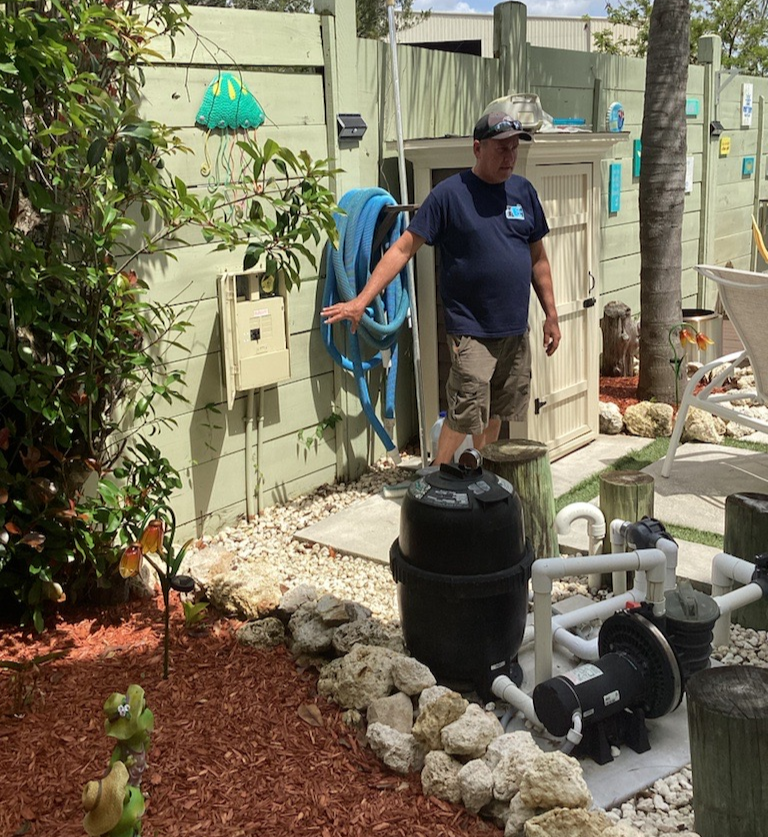 A man in a blue shirt is standing next to a hose