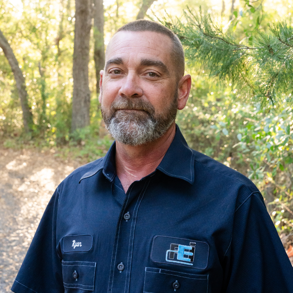 Faulkner Electric Electrician, Ryan Long, in front of our work vans with Faulkner Electric Logo