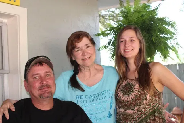 A man , a woman and a girl are posing for a picture.