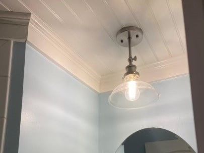 A light fixture is hanging from the ceiling in a bathroom.