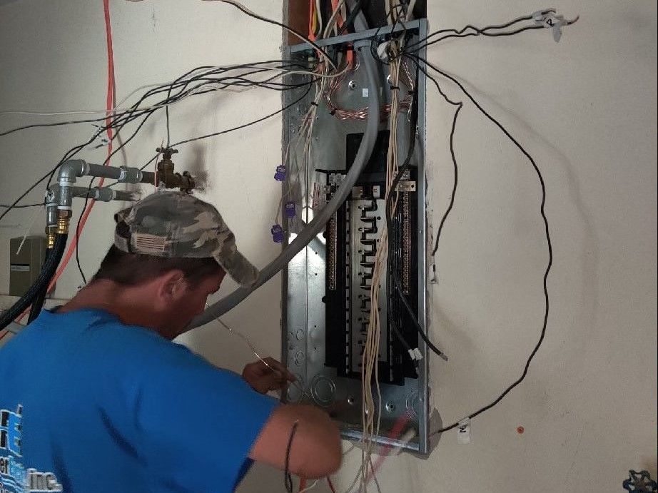 A man in a blue shirt is working on an electrical panel