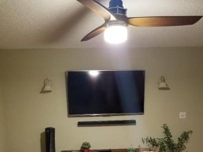 A living room with a flat screen tv and a ceiling fan.