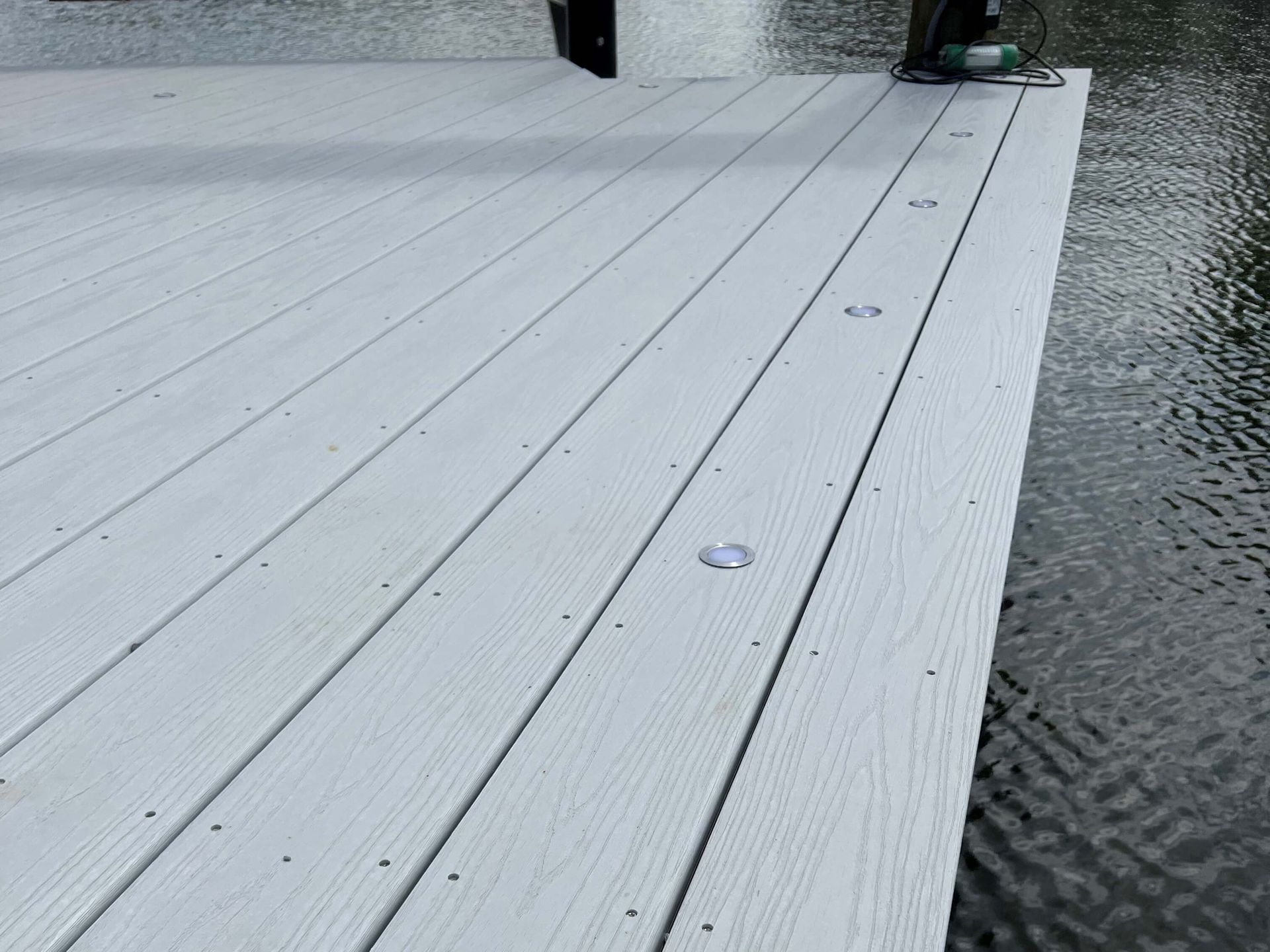 A white wooden deck is sitting next to a body of water.