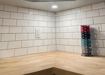 A kitchen with white tiles and a wooden counter top.