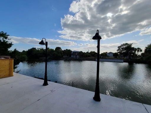 Two street lights are sitting next to a body of water.