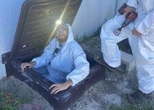 A man in a white suit is sitting in a hole in the ground.