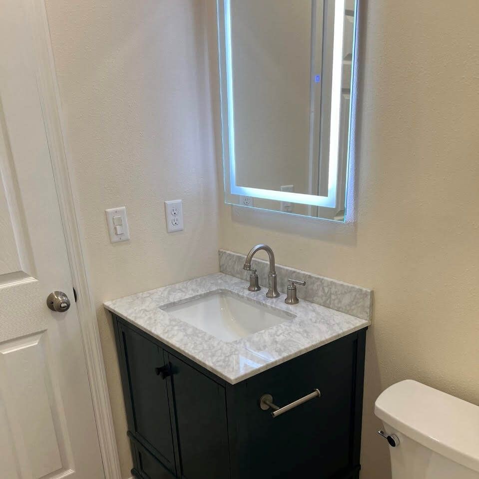 A bathroom with a sink , toilet and mirror.