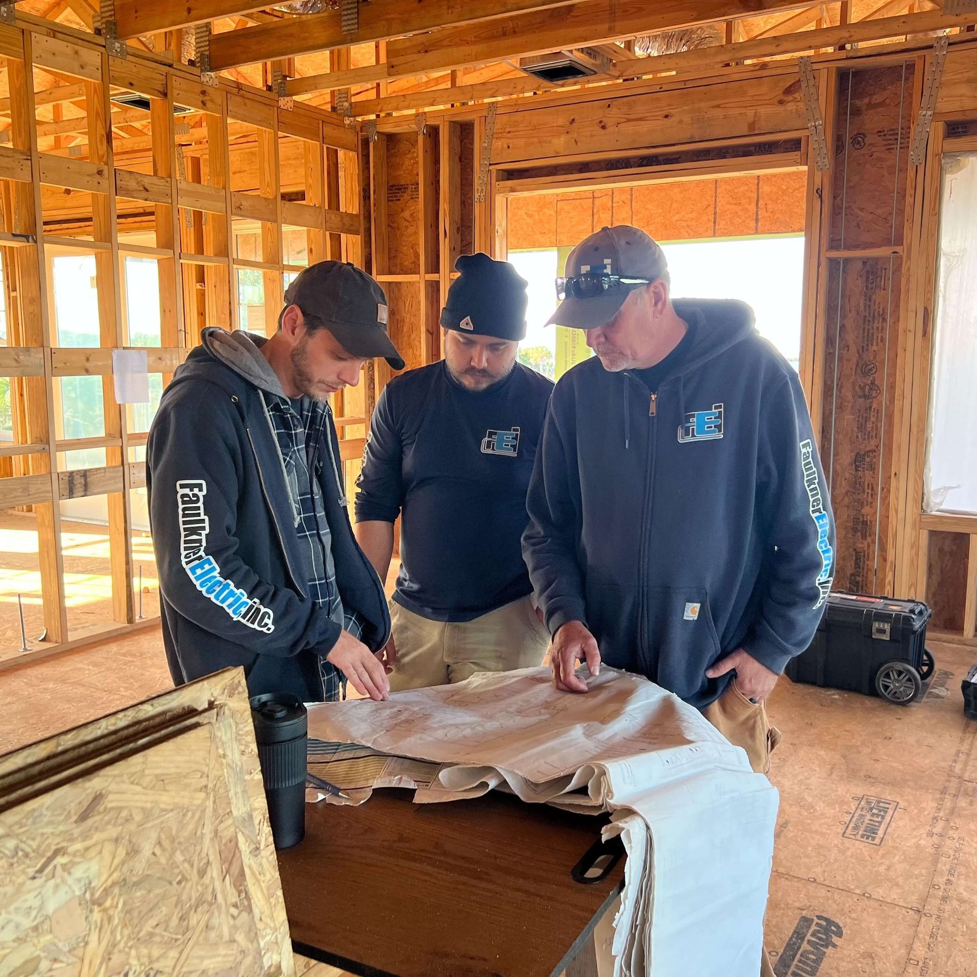 Three men are looking at a blueprint in a building under construction