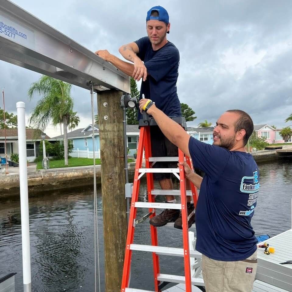 Two men are working on a boat and one is on a ladder