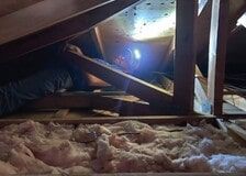 A light is shining through a hole in the ceiling of an attic.