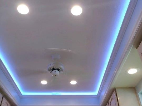 A ceiling with a ceiling fan and blue lights on it.