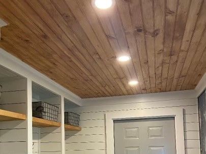 A room with a wooden ceiling and shelves.