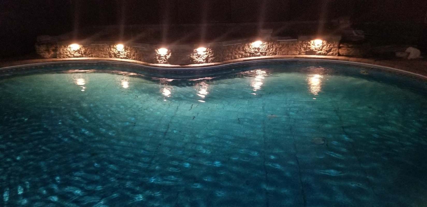 Une grande piscine est éclairée la nuit.