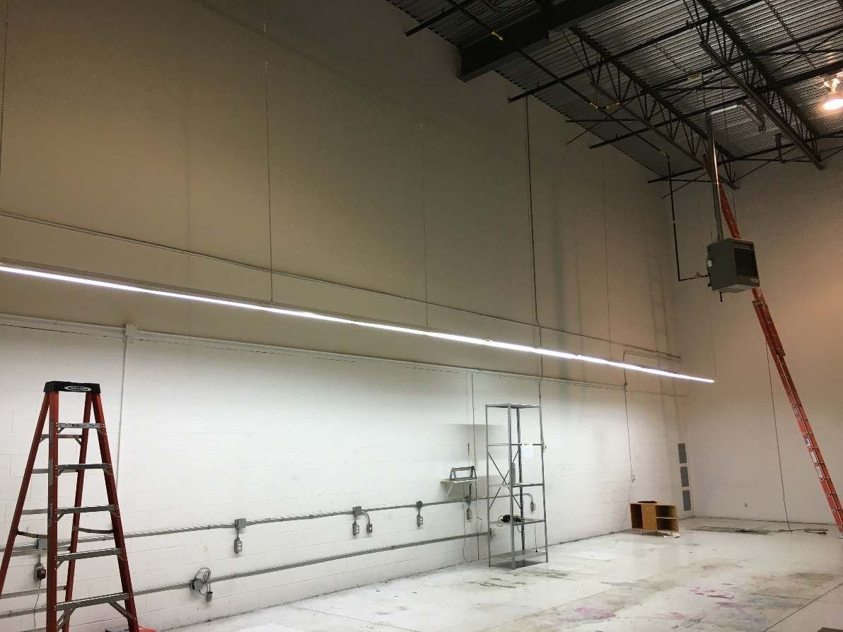 Une grande pièce vide avec une échelle et des lumières suspendues au plafond.