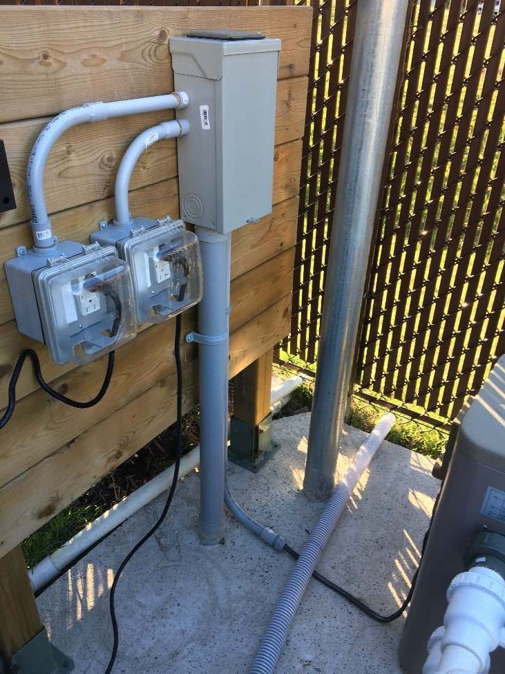 Un coffret électrique se trouve à côté d'une clôture en bois.