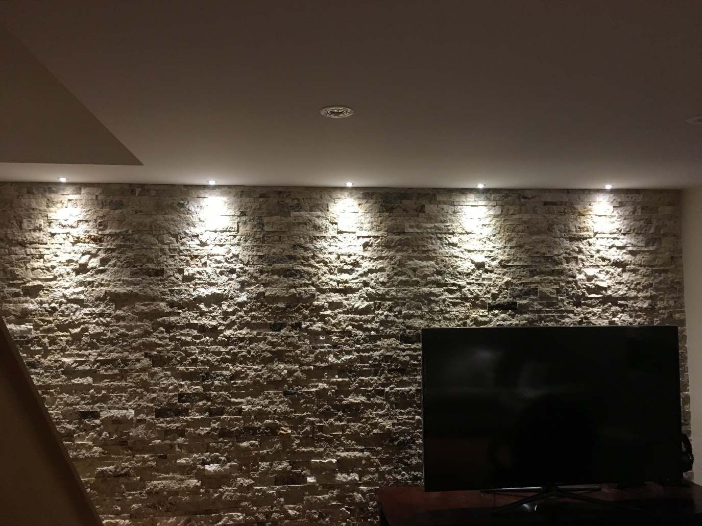 Un salon avec un mur de briques et une télévision à écran plat