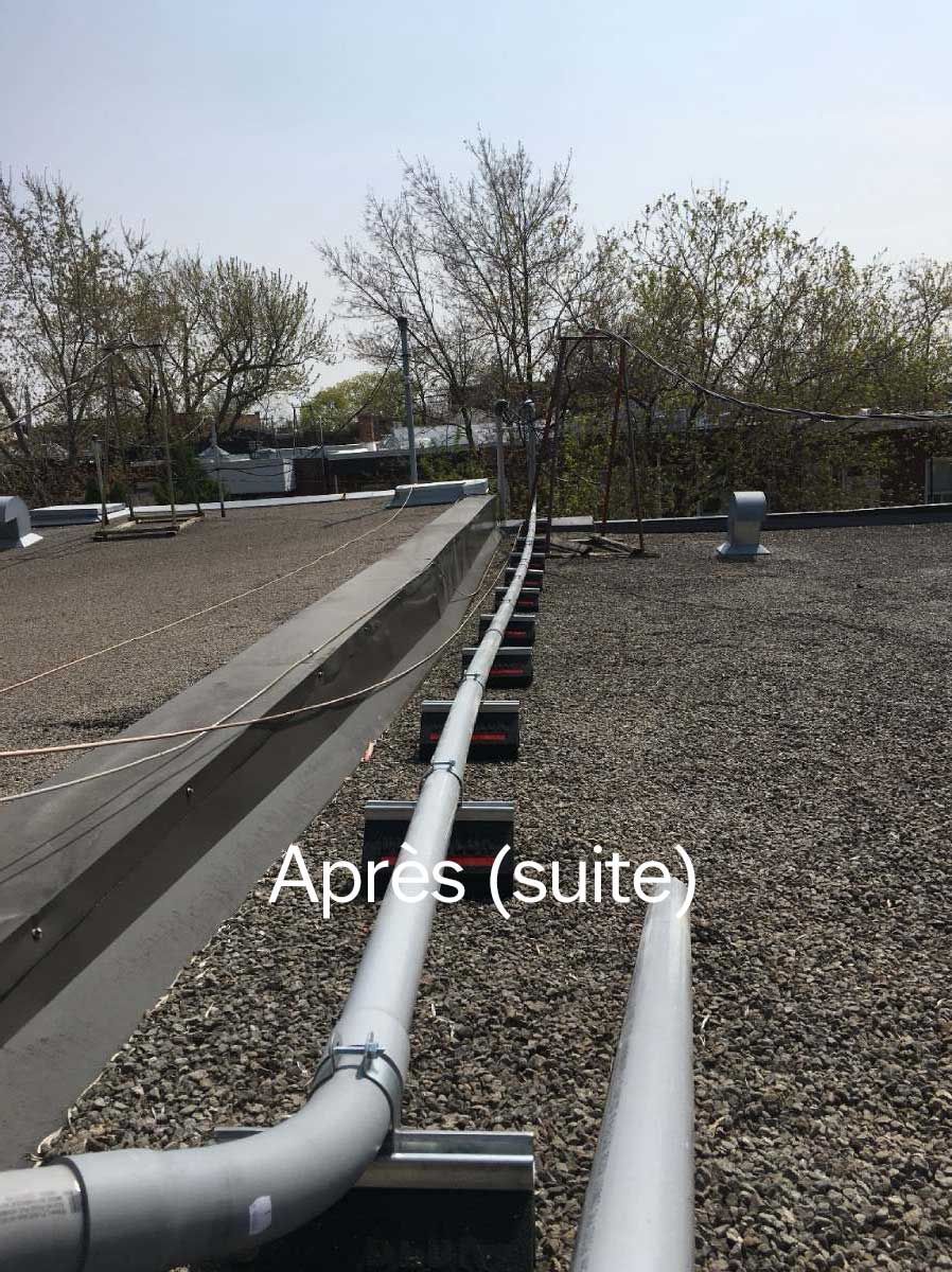 A row of pipes on top of a gravel covered roof.