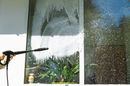 A person is cleaning a window with a high pressure washer.