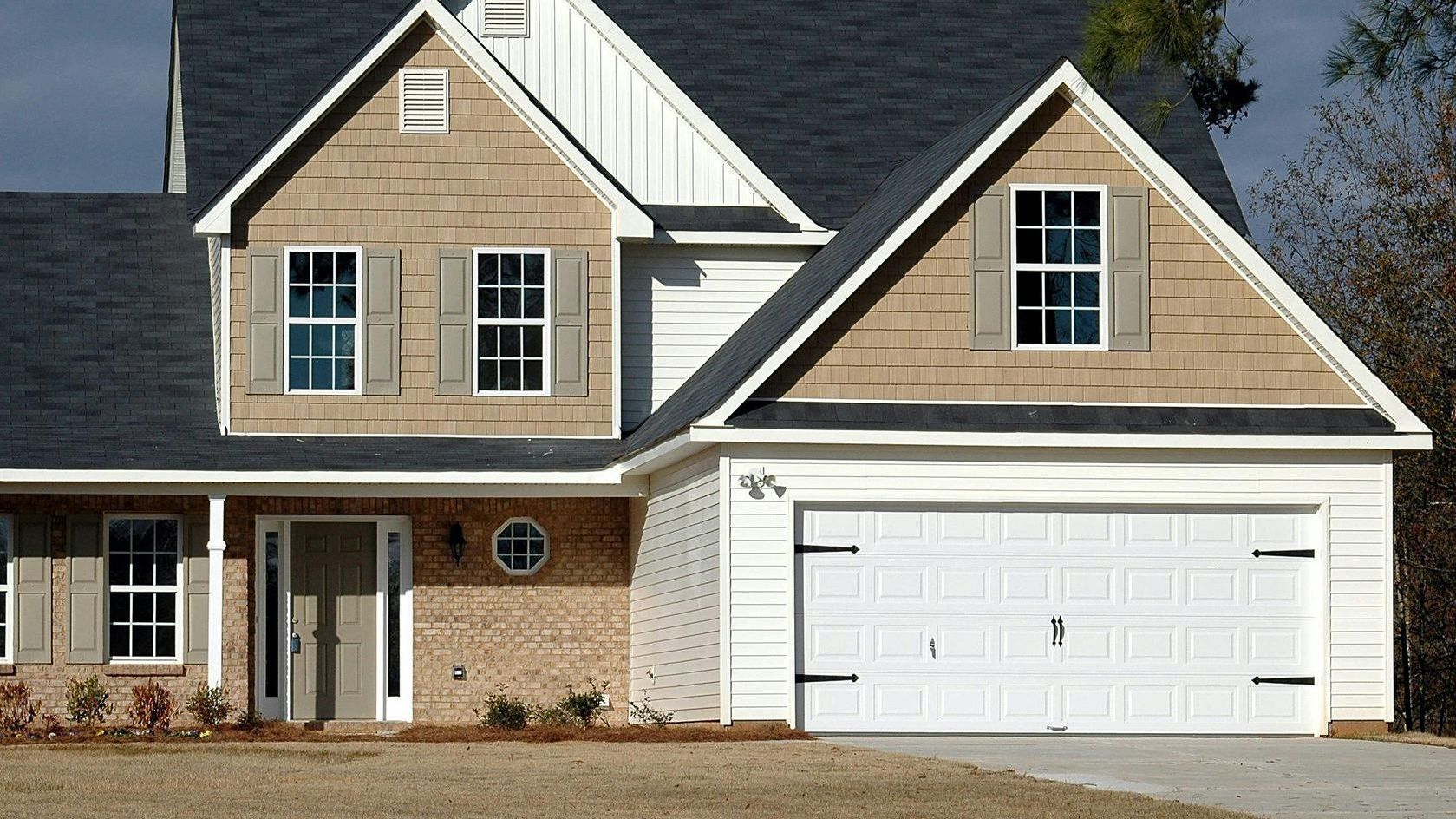 Stately brick home with fresh exterior paint, featuring a crisp white garage door, highlighting professional exterior painting craftsmanship