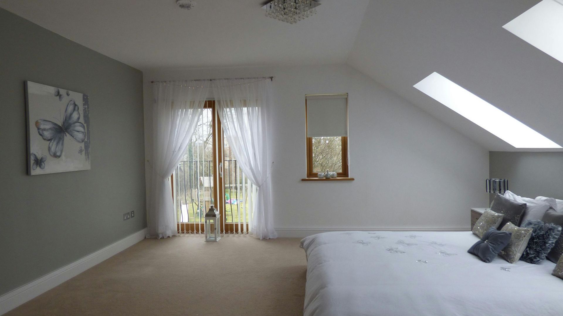 Freshly painted bedroom featuring a comfortable bed, modern sliding glass doors, and a natural light-enhancing skylight, showcasing professional interior painting results