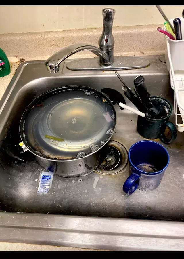 Amaya's Cleaning Service - A dirty kitchen sink with a pot and a cup in it.