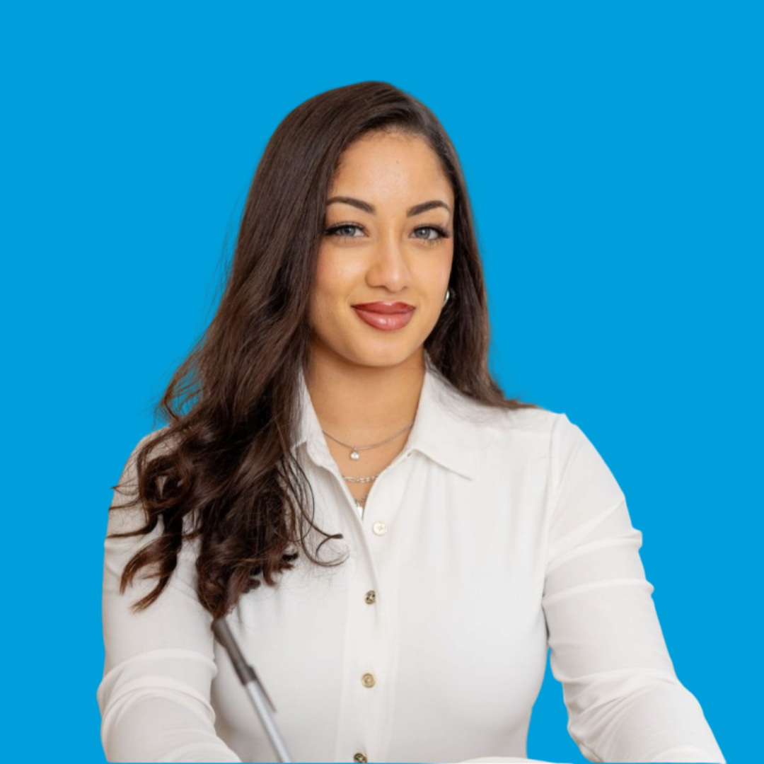 Woman with long dark hair, wearing a white shirt, smiling, blue background.