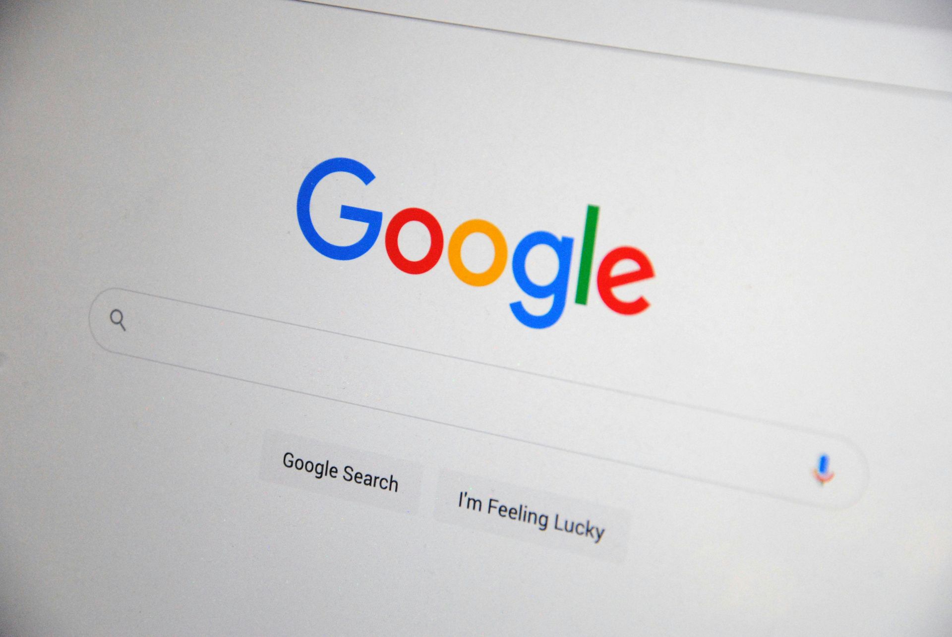 Google homepage on a laptop screen with the search bar and “Google Search” buttons visible