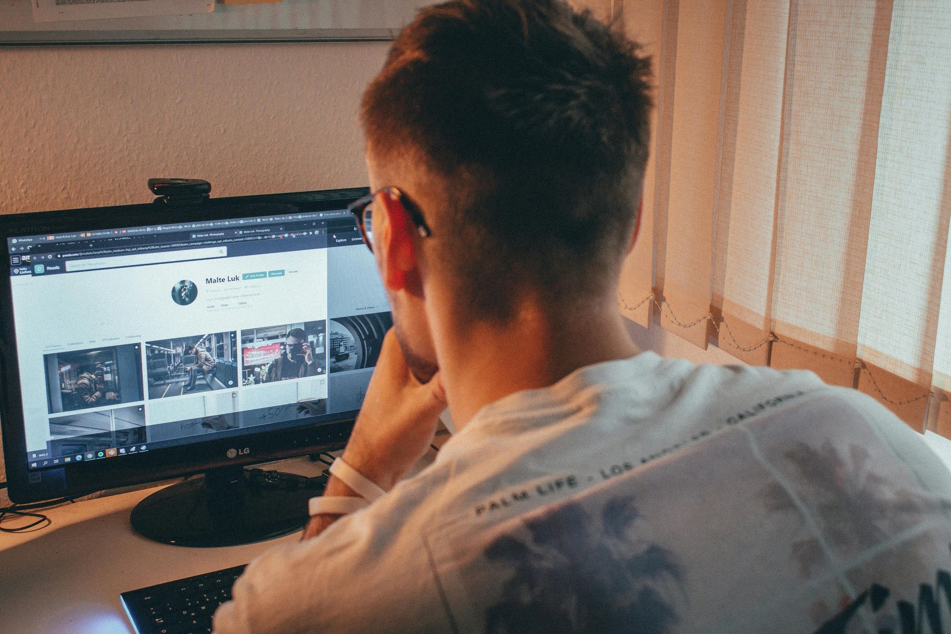 Person sitting at a desk, viewing a computer monitor in a dim room