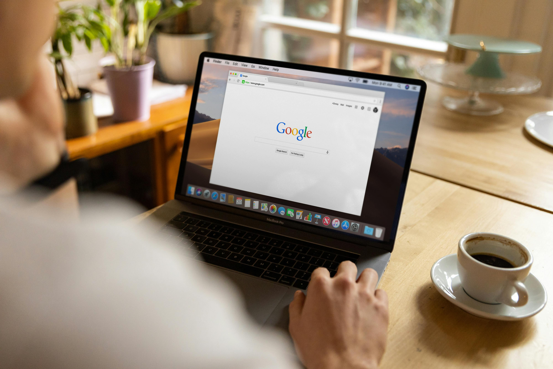 Person using a laptop at a table with coffee, looking at Google.