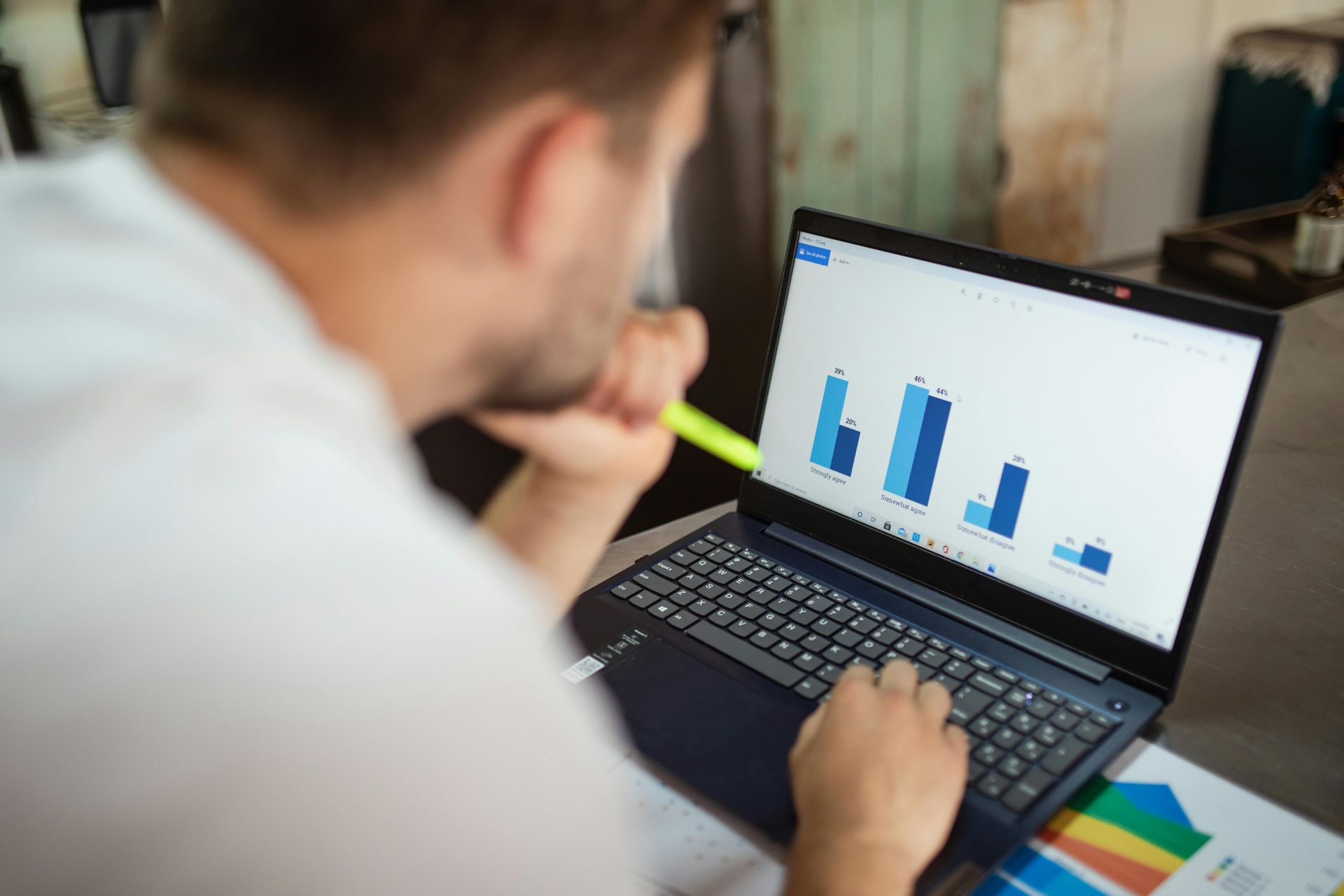 Person reviewing blue bar charts on a laptop in an office setting