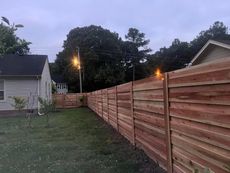 A wooden fence is in the backyard of a house.