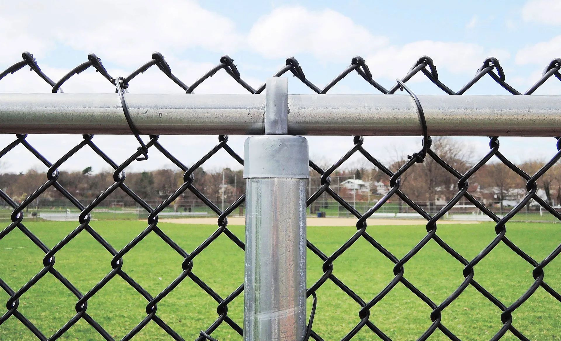 A chain link fence is surrounding a baseball field.