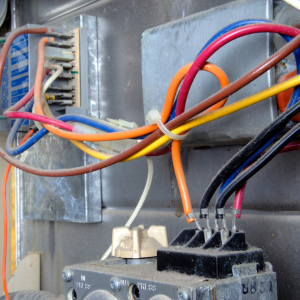 Close-up of colored electrical wires connected to a terminal block inside a metal enclosure