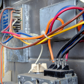 Close-up of colored electrical wires connected to a terminal block inside a metal enclosure