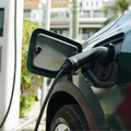 Electric vehicle charging port with cable plugged into a dark car outdoors