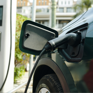 Electric vehicle charging port with cable plugged into a dark car outdoors