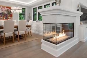 Modern dining room with a white corner fireplace and glass-encased flames