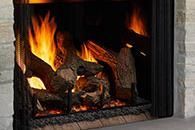Fire burning in a brick fireplace with logs and glowing embers