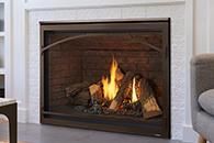Lit fireplace with flames in a brick hearth and dark wood surround