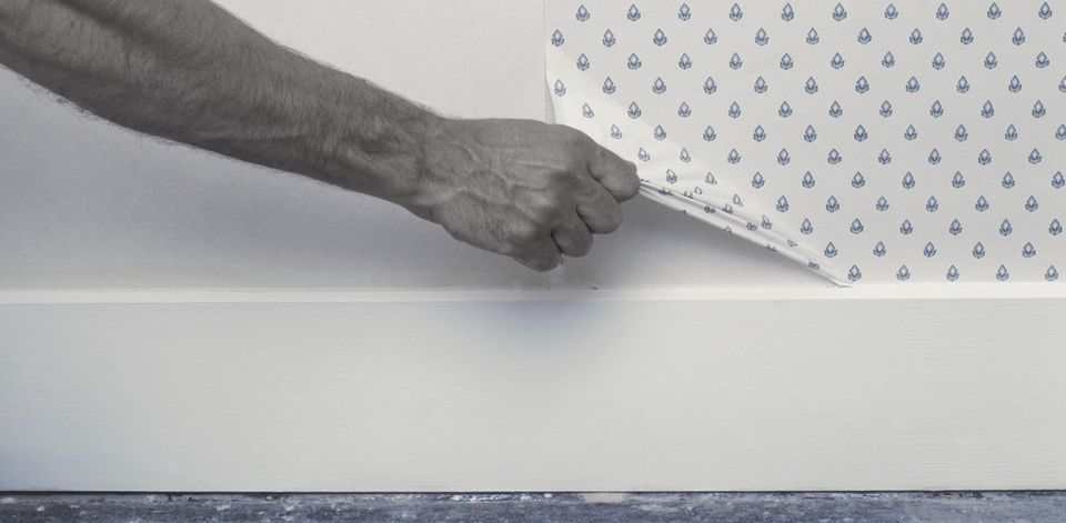 man stripping wallpaper by hand