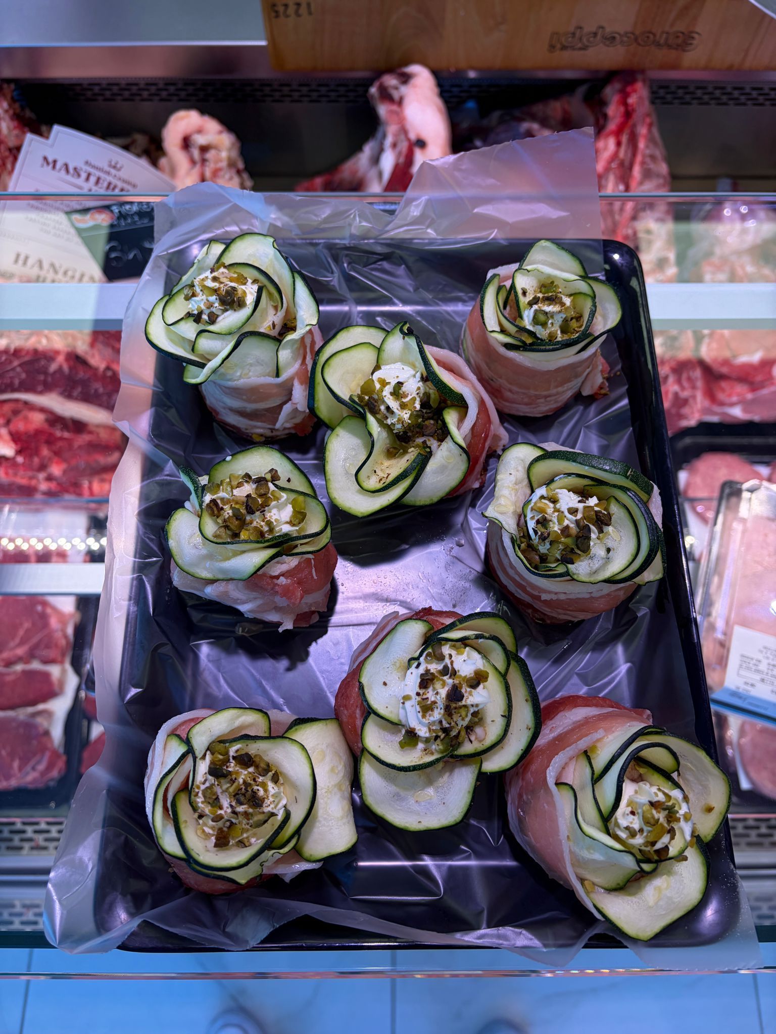 Vassoio di antipasti arrotolati con cetriolo su carta stagnola al banco di una gastronomia
