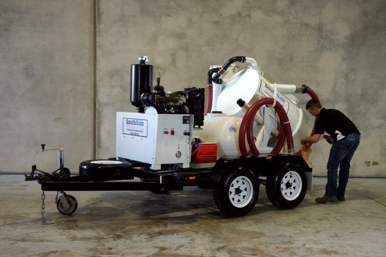 A man is standing next to a vacuum cleaner on a trailer