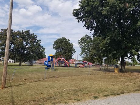 A park with a playground and trees on a sunny day