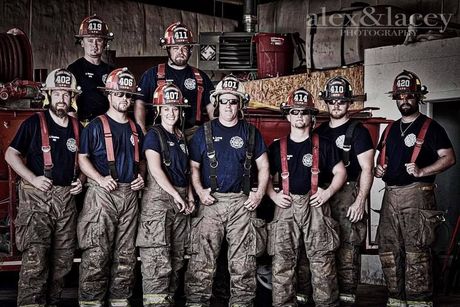 A group of firefighters are posing for a picture in front of a fire truck